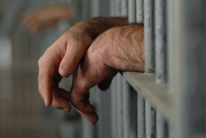 Male hands sticking out from his jail cell