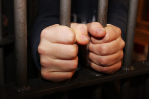 white male hands gripping prison bars