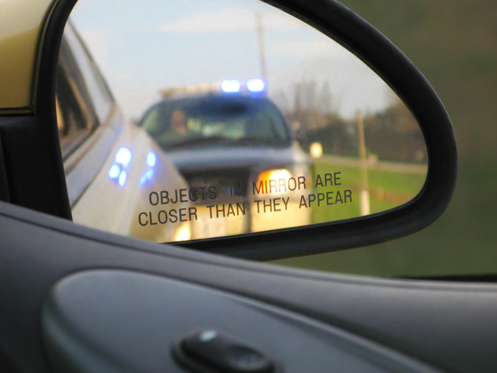 Police car in the rear view of a car mirror