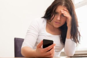 Distressed woman looking at her cell phone